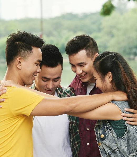 four-teen-friends-hugging-outdoors-river-min 1 four-teen-friends-hugging-outdoors-river-min 1